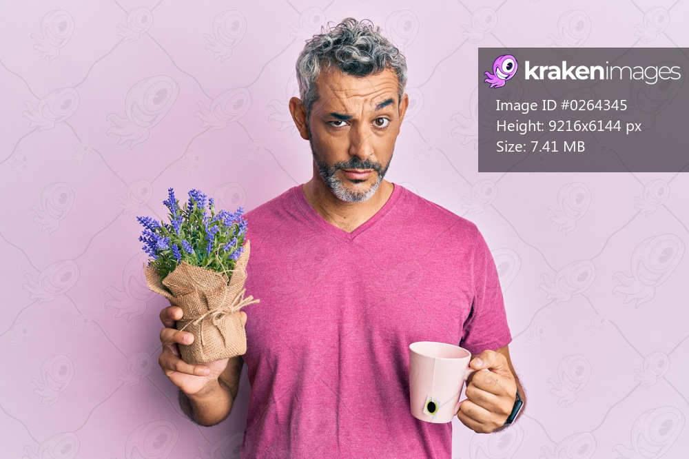Middle age grey-haired man drinking a cup of infused lavender skeptic and nervous, frowning upset because of problem. negative person. 