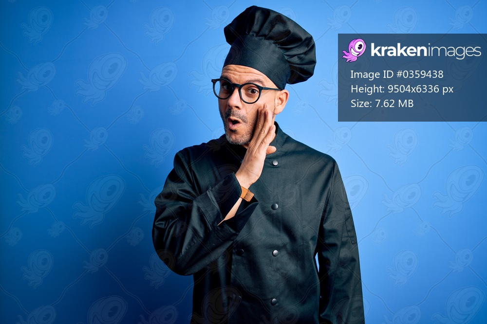 Young handsome chef man wearing cooker uniform and hat over isolated blue background hand on mouth telling secret rumor, whispering malicious talk conversation