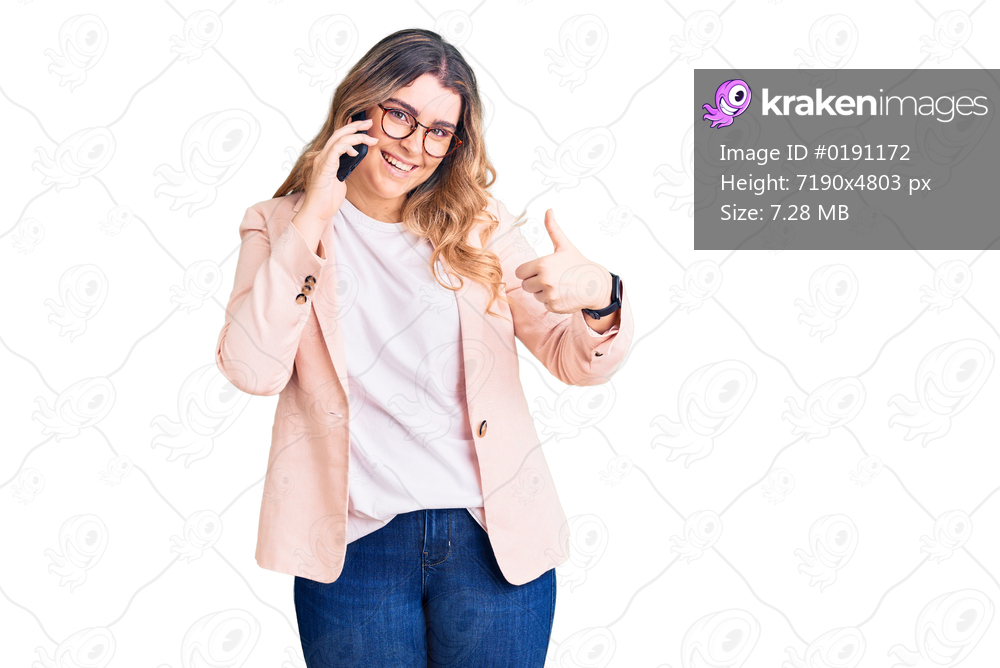 Young caucasian woman having conversation talking on the smartphone smiling happy and positive, thumb up doing excellent and approval sign 