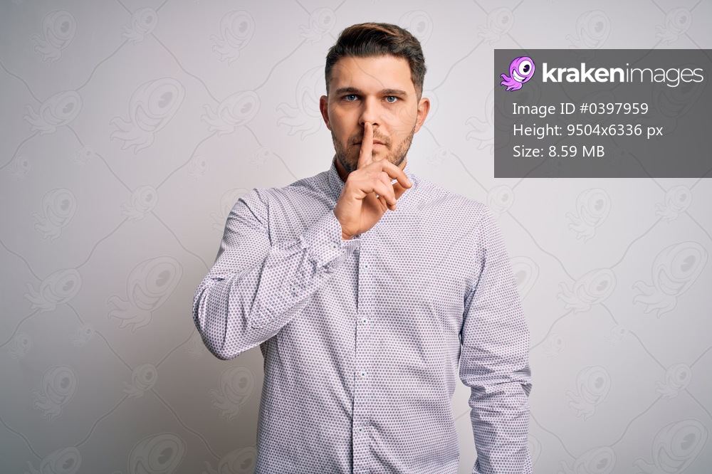 Young business man with blue eyes standing over isolated background asking to be quiet with finger on lips. Silence and secret concept.