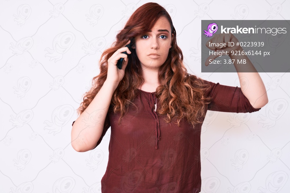 Young beautiful woman having conversation talking on the smartphone with angry face, negative sign showing dislike with thumbs down, rejection concept 