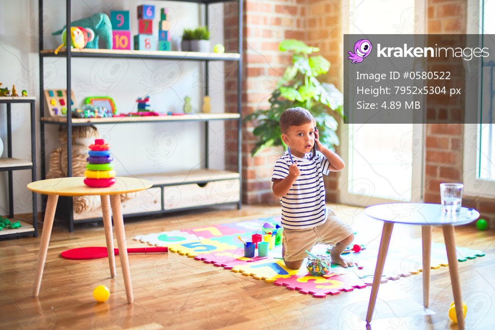 Beautiful toddler boy talking on the smartphone at kindergarten