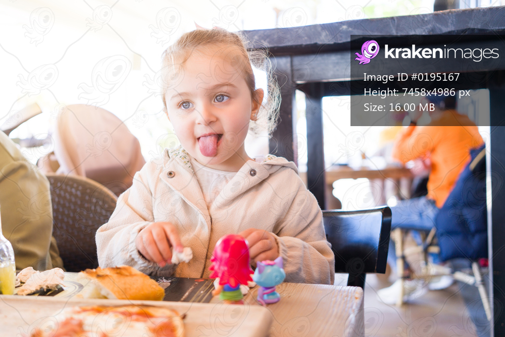 Beautiful toddler child girl sitting on baby highchair  playing with toys on the table