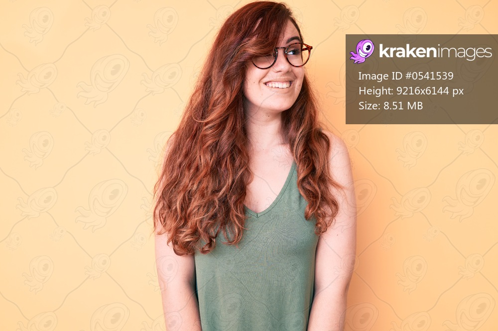 Young beautiful woman wearing casual clothes and glasses looking away to side with smile on face, natural expression. laughing confident. 