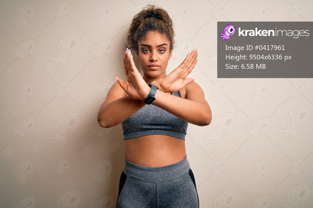 Young african american sportswoman doing sport wearing sportswear over white background Rejection expression crossing arms doing negative sign, angry face