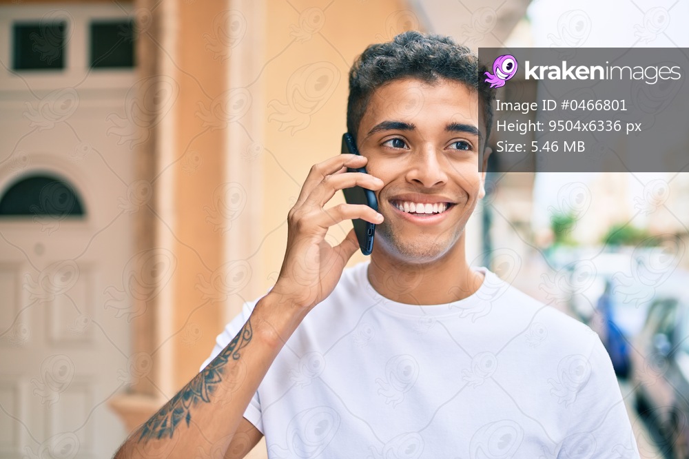 Young latin man smiling happy talking on the smartphone walking at the city.