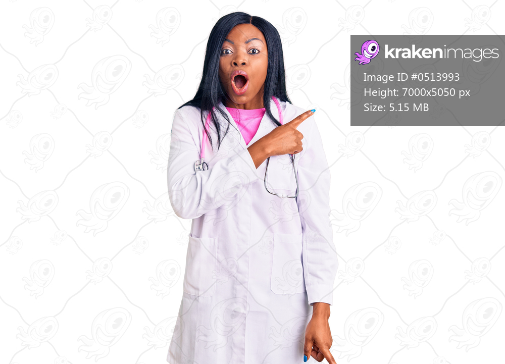 Young african american woman wearing doctor stethoscope surprised pointing with finger to the side, open mouth amazed expression. 
