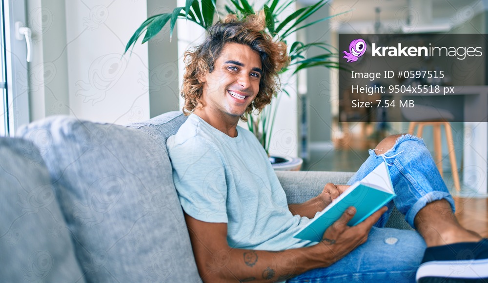 Young hispanic man smiling happy reading book at home