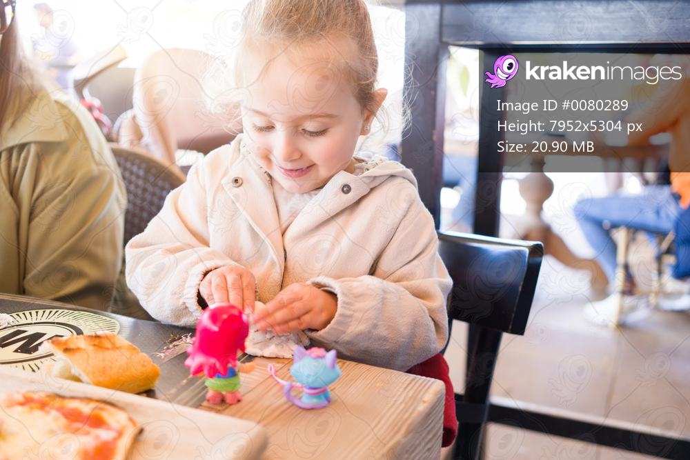 Beautiful toddler child girl sitting on baby highchair  playing with toys on the table