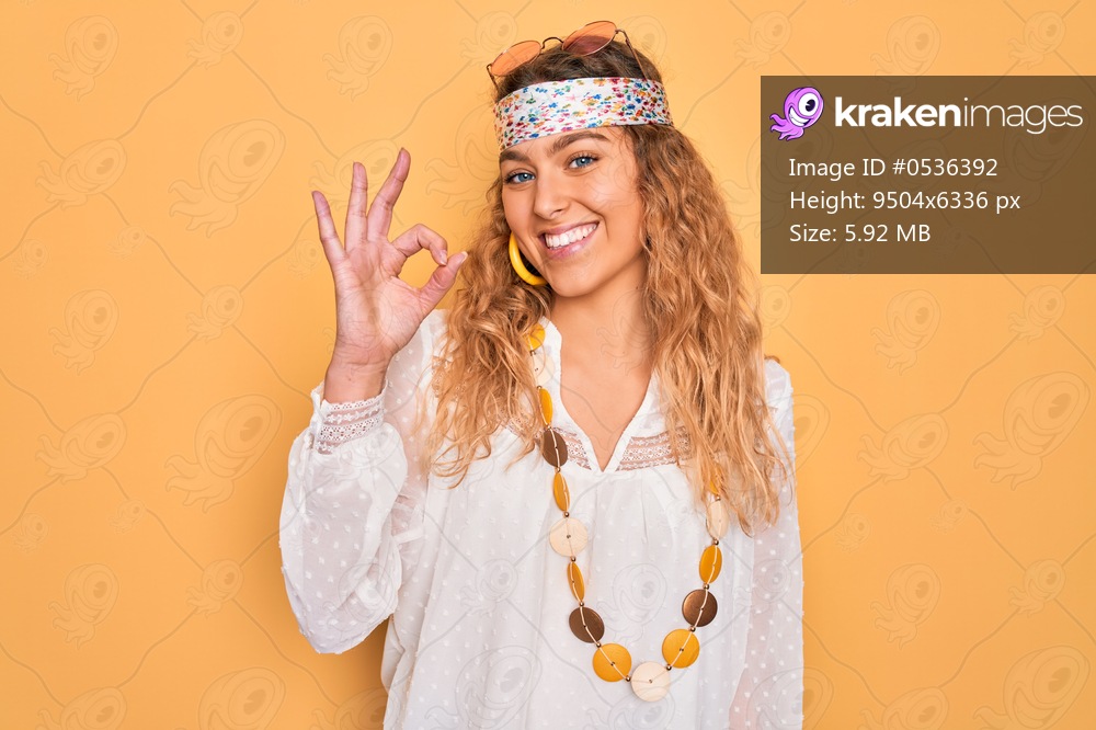 Young beautiful blonde hippie woman with blue eyes wearing sunglasses and accessories smiling positive doing ok sign with hand and fingers. Successful expression.