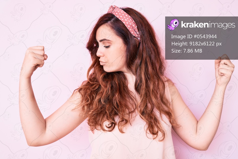 Young beautiful woman wearing casual clothes showing arms muscles smiling proud. fitness concept. 