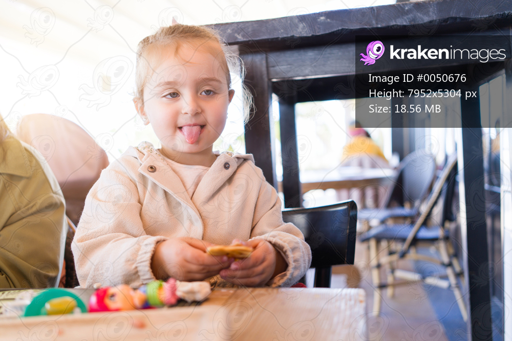 Beautiful toddler child girl sitting on baby highchair  playing with toys on the table