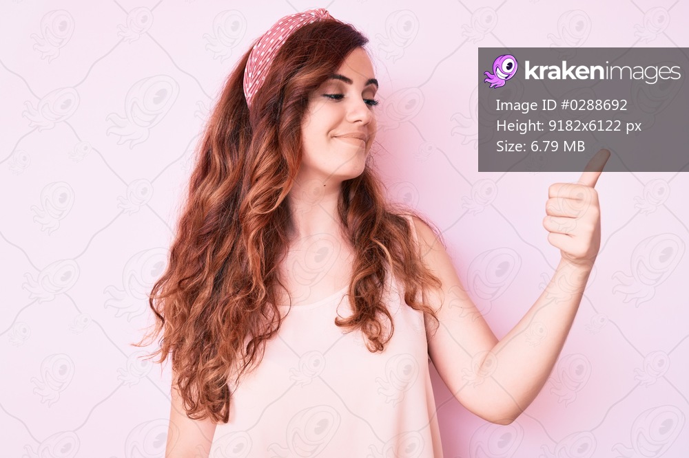 Young beautiful woman wearing casual clothes looking proud, smiling doing thumbs up gesture to the side 