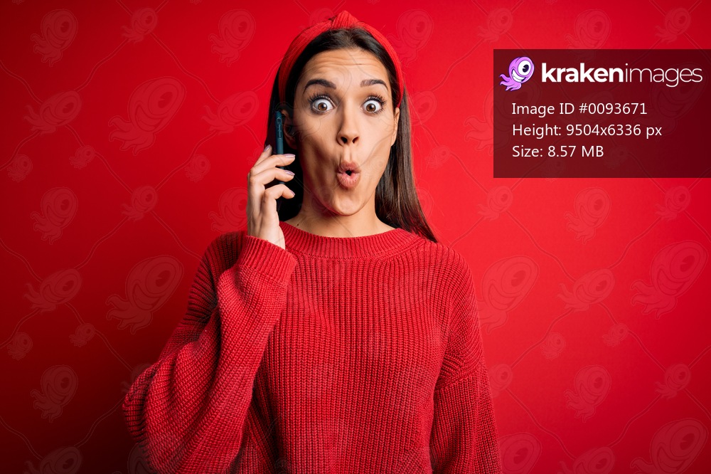 Young beautiful brunette woman having conversation talking on the smartphone scared in shock with a surprise face, afraid and excited with fear expression