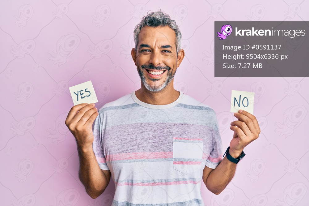 Middle age grey-haired man holding yes and no reminder smiling with a happy and cool smile on face. showing teeth. 