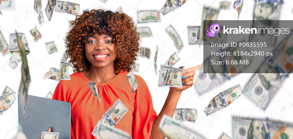 Young african american woman working using computer laptop smiling happy pointing with hand and finger to the side