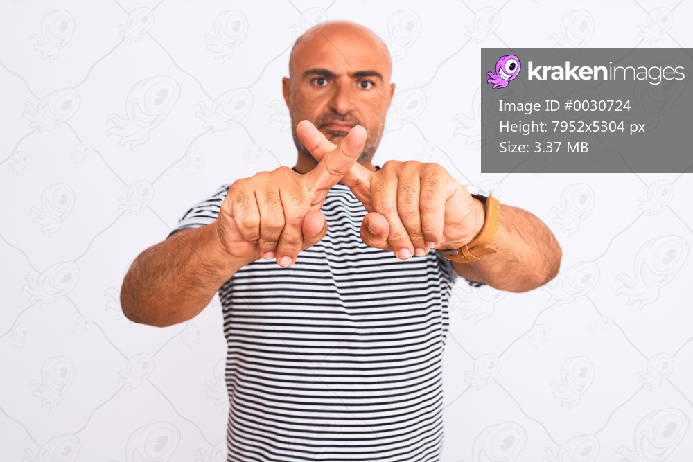 Middle age handsome man wearing striped navy t-shirt over isolated white background Rejection expression crossing fingers doing negative sign