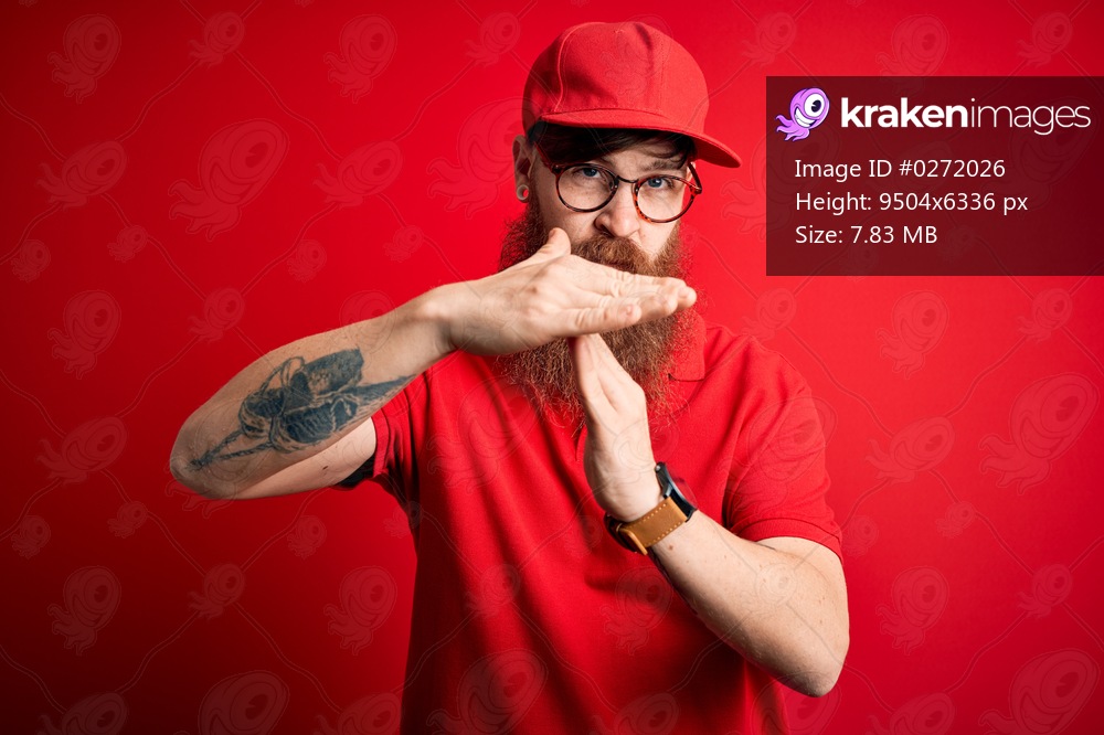 Young handsome delivery man wearing glasses and red cap over isolated background Doing time out gesture with hands, frustrated and serious face