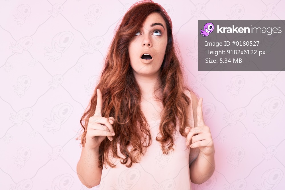 Young beautiful woman wearing casual clothes amazed and surprised looking up and pointing with fingers and raised arms. 