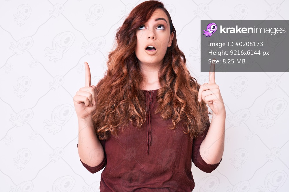 Young beautiful woman wearing casual clothes amazed and surprised looking up and pointing with fingers and raised arms. 