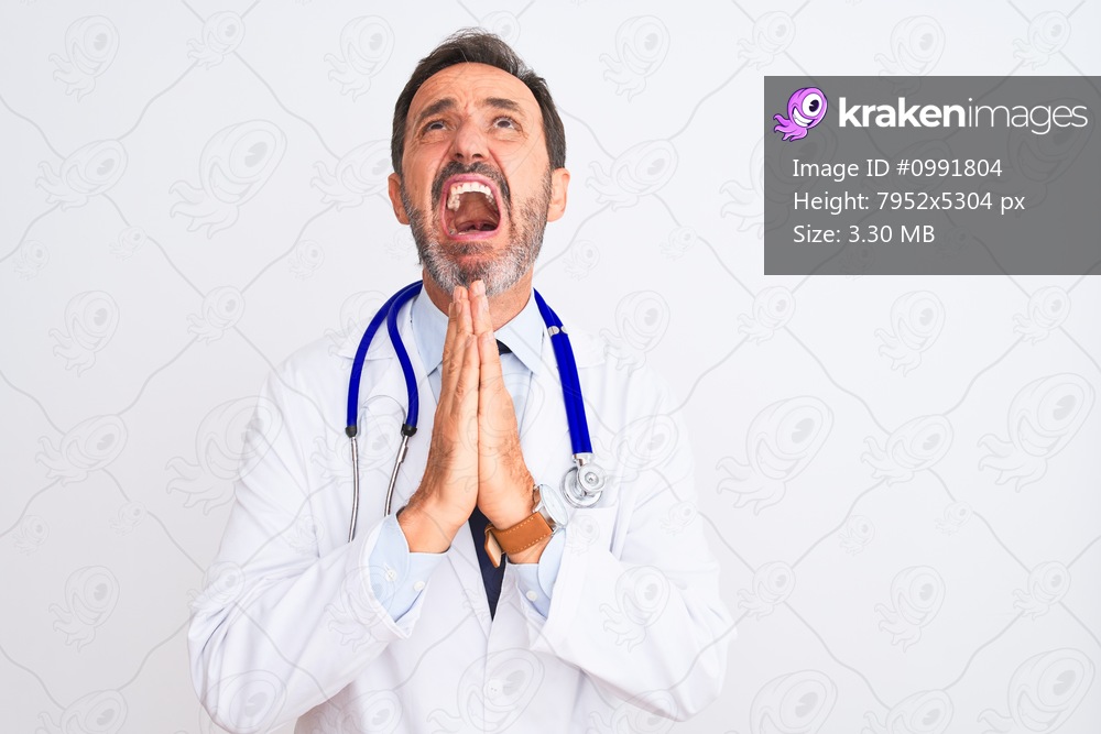 Middle age doctor man wearing coat and stethoscope standing over isolated white background begging and praying with hands together with hope expression on face very emotional and worried. Asking for forgiveness. Religion concept.