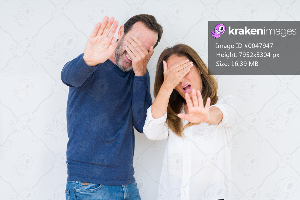 Beautiful middle age couple in love over isolated background covering eyes with hands and doing stop gesture with sad and fear expression. Embarrassed and negative concept.