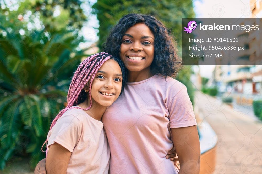 Beautiful african american mother and daughter smiling happy and hugging. Standing with smile on face standing at the park.