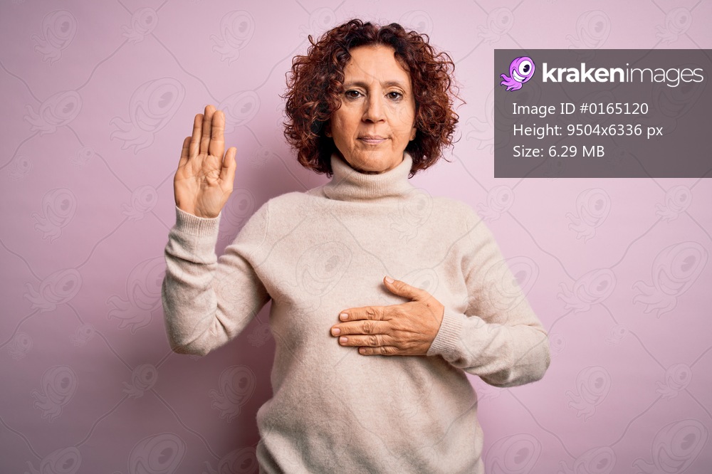 Middle age beautiful curly hair woman wearing casual turtleneck sweater over pink background Swearing with hand on chest and open palm, making a loyalty promise oath