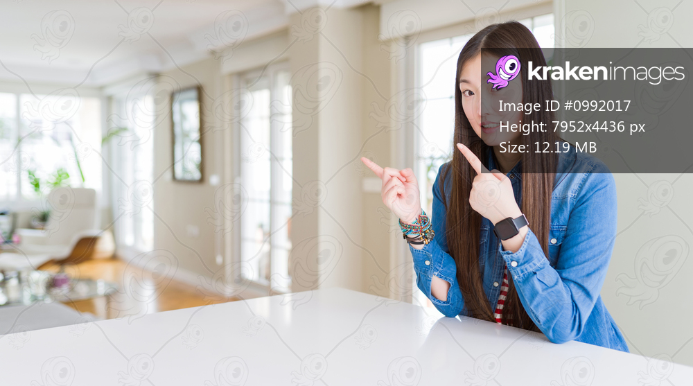 Young beautiful asian woman with long hair wearing denim jacket Pointing aside worried and nervous with both hands, concerned and surprised expression