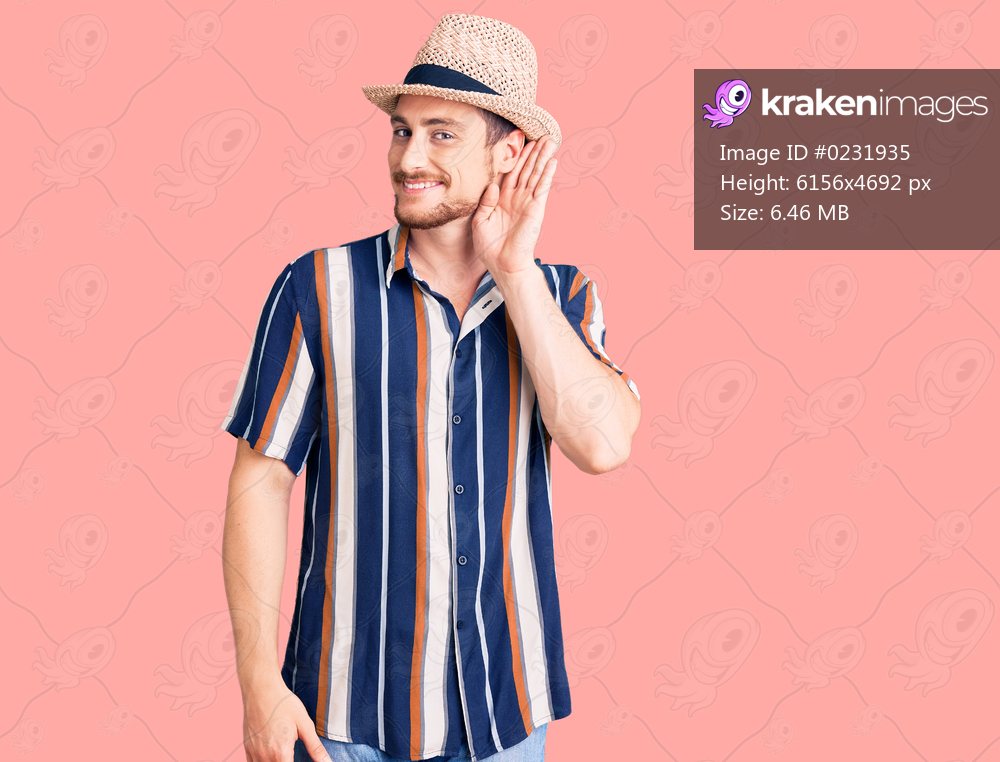Young handsome caucasian man wearing summer hat smiling with hand over ear listening an hearing to rumor or gossip. deafness concept. 