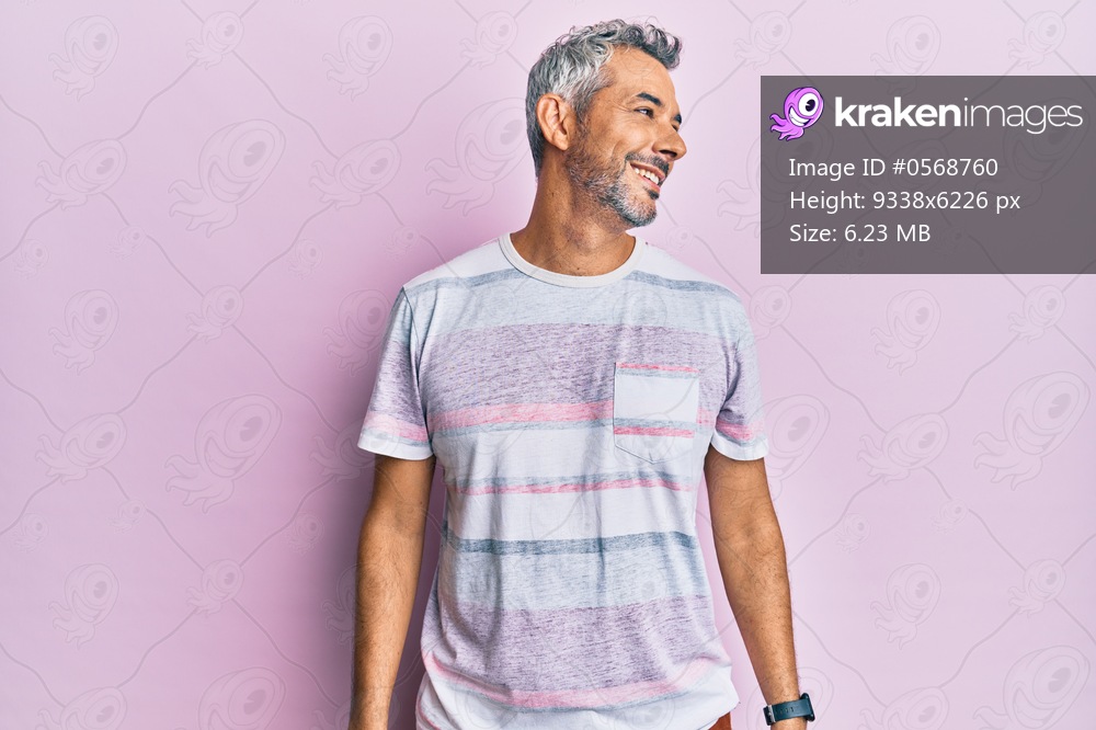 Middle age grey-haired man wearing casual clothes looking away to side with smile on face, natural expression. laughing confident. 