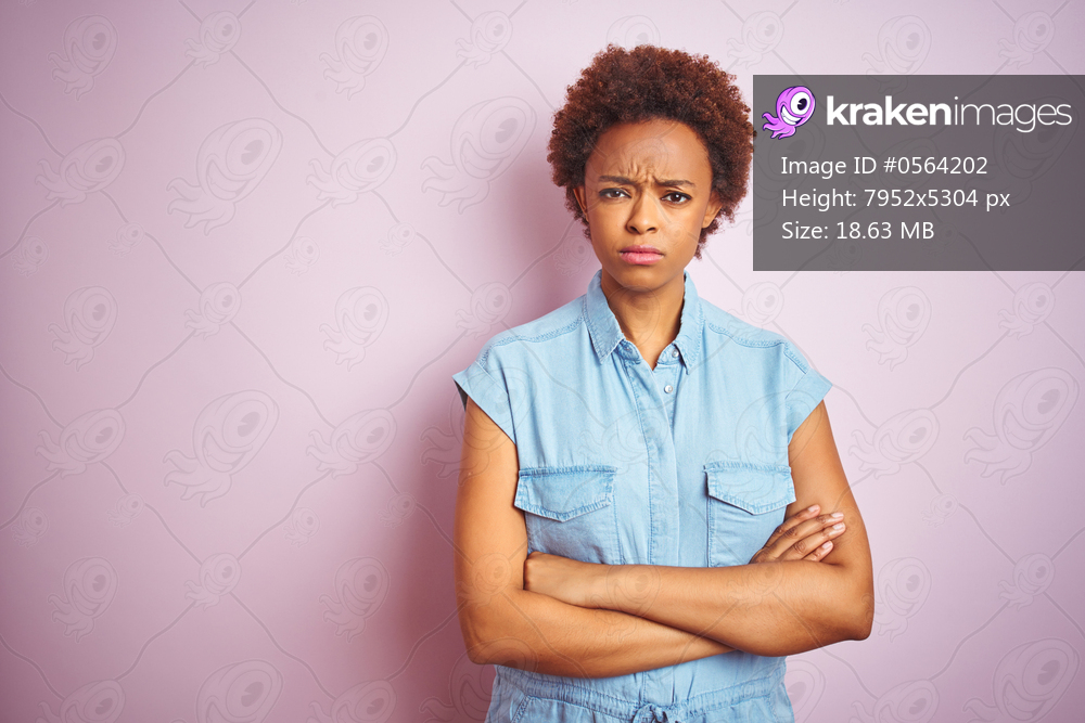 Young beautiful african american woman with afro hair over isolated pink background skeptic and nervous, disapproving expression on face with crossed arms. Negative person.