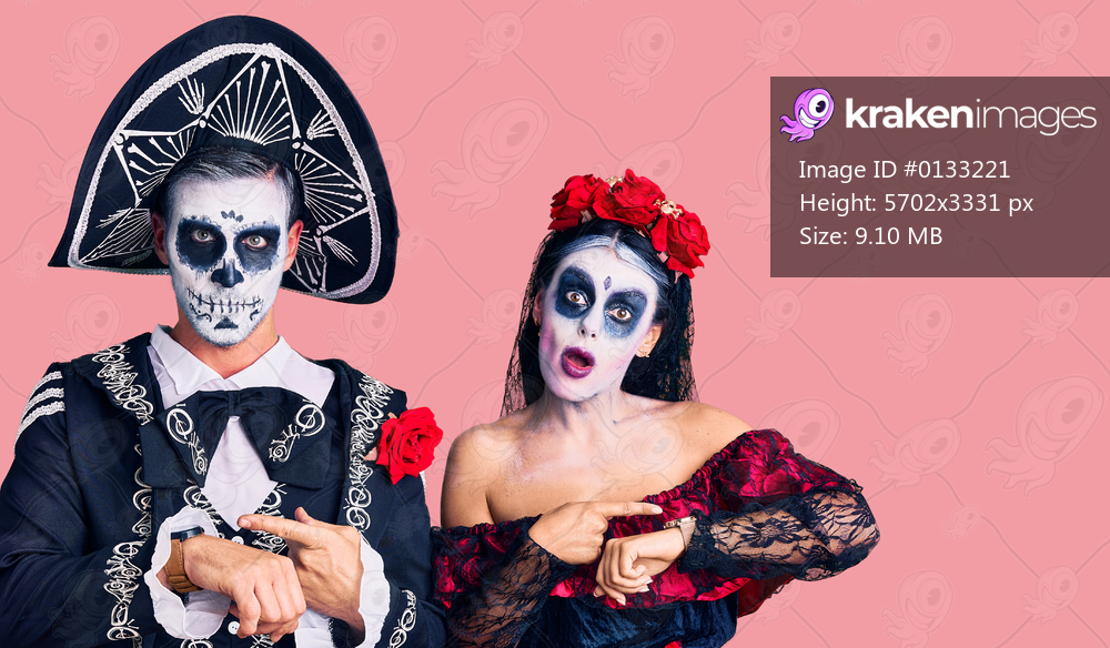 Young couple wearing mexican day of the dead costume over background in hurry pointing to watch time, impatience, upset and angry for deadline delay 