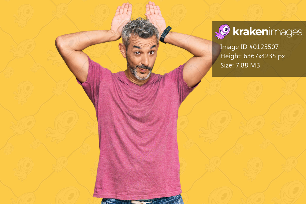 Middle age grey-haired man wearing casual clothes doing bunny ears gesture with hands palms looking cynical and skeptical. easter rabbit concept. 