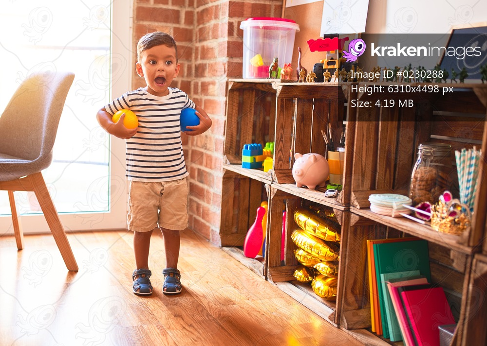Beautiful toddler boy playing with colored small balls at kindergarten