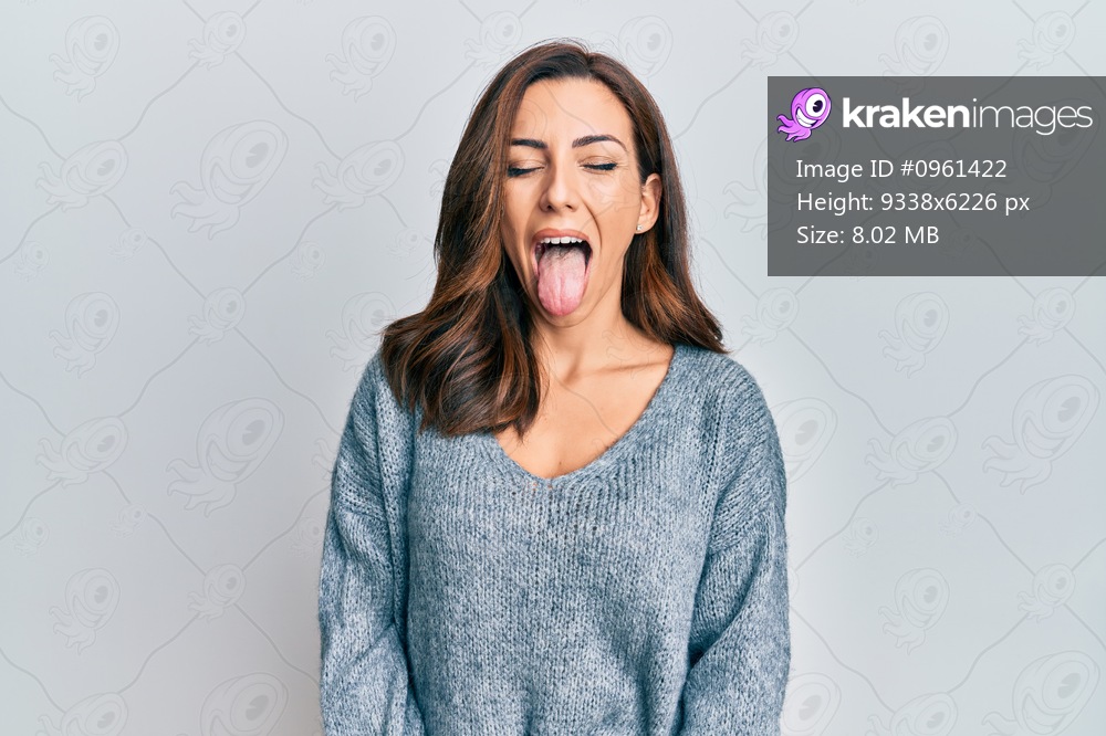 Young brunette woman wearing casual winter sweater sticking tongue out happy with funny expression. emotion concept. 