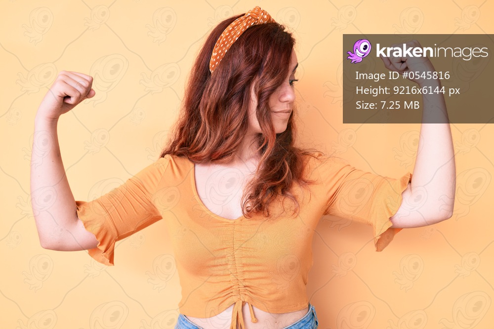 Young beautiful woman wearing casual clothes showing arms muscles smiling proud. fitness concept. 