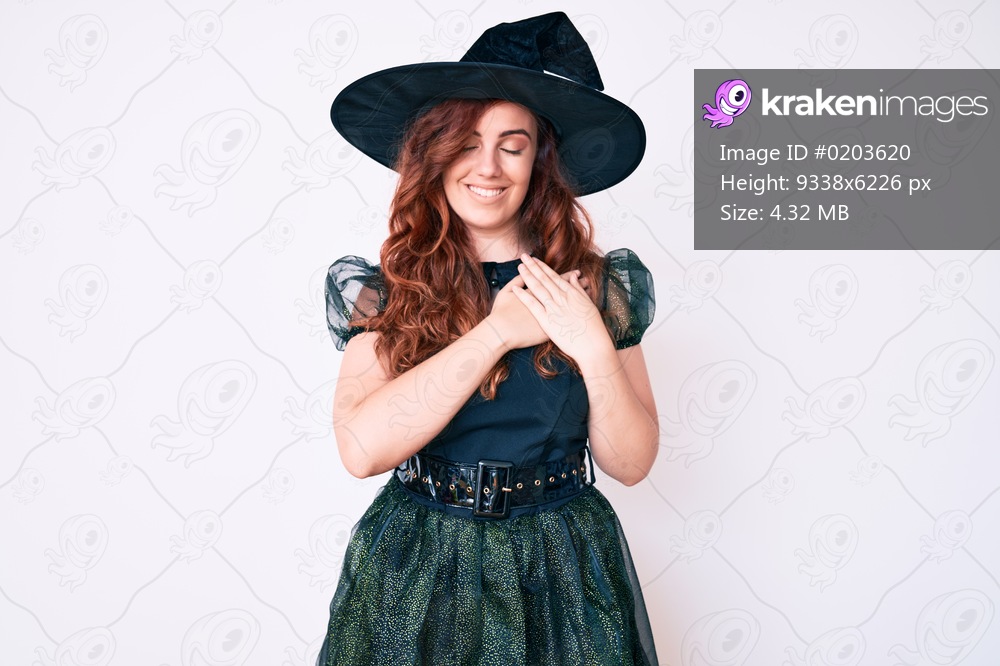 Young beautiful woman wearing witch halloween costume smiling with hands on chest with closed eyes and grateful gesture on face. health concept. 