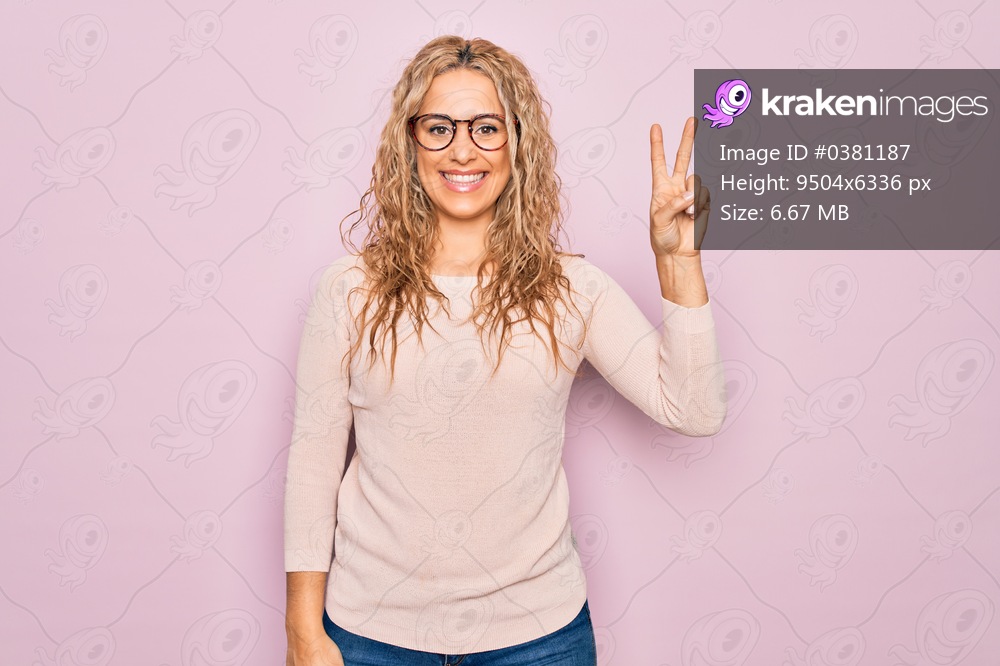 Young beautiful blonde woman wearing casual sweater and glasses over pink background showing and pointing up with fingers number two while smiling confident and happy.