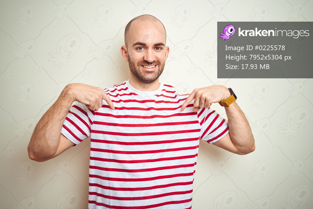 Young bald man with beard wearing casual striped red t-shirt over white isolated background looking confident with smile on face, pointing oneself with fingers proud and happy.