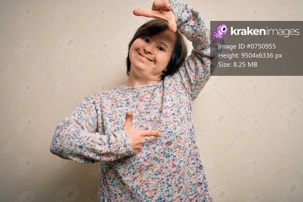 Young down syndrome woman standing over isolated background smiling making frame with hands and fingers with happy face. Creativity and photography concept.