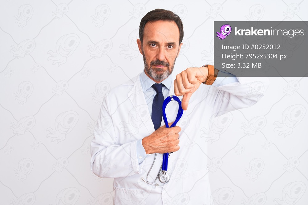 Middle age doctor man wearing coat holding stethoscope over isolated white background with angry face, negative sign showing dislike with thumbs down, rejection concept