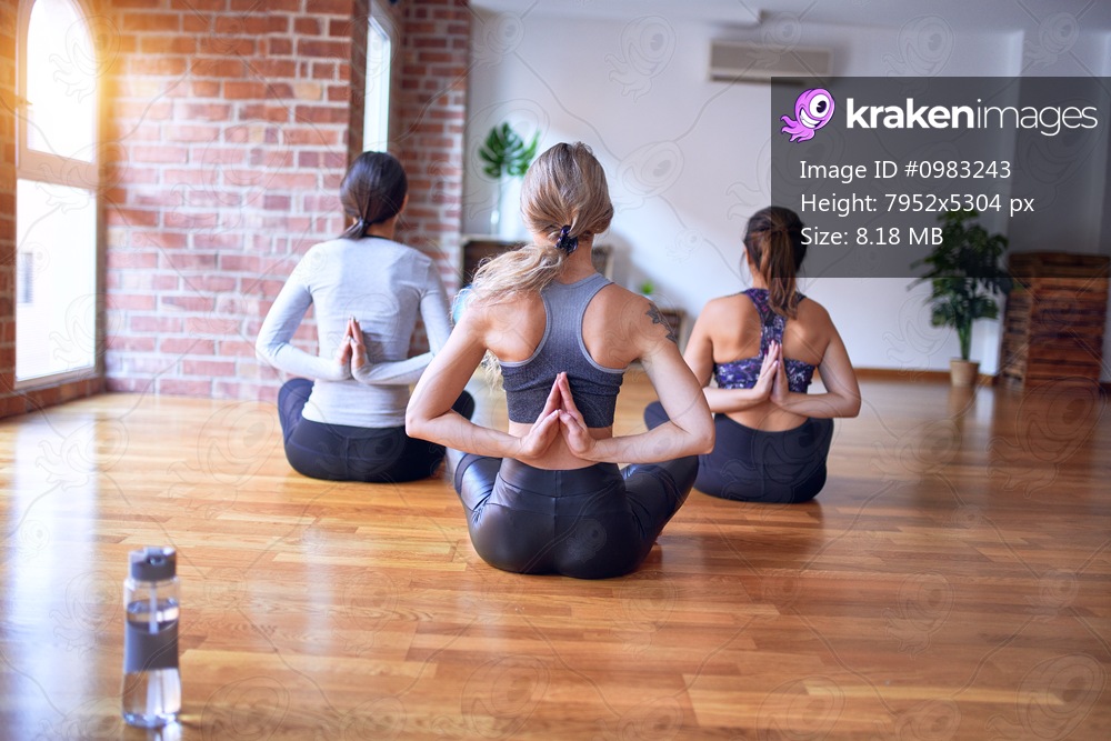 Young beautiful group of sportswomen practicing yoga at gym