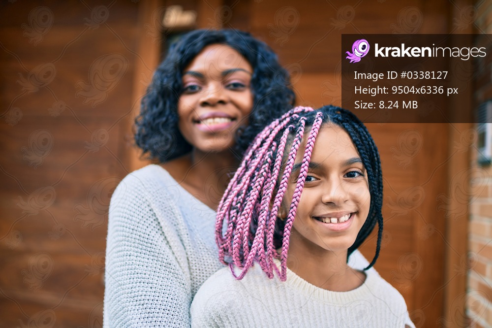 Beautiful african american mother and daughter smiling happy and hugging. Standing with smile on face standing at the city.