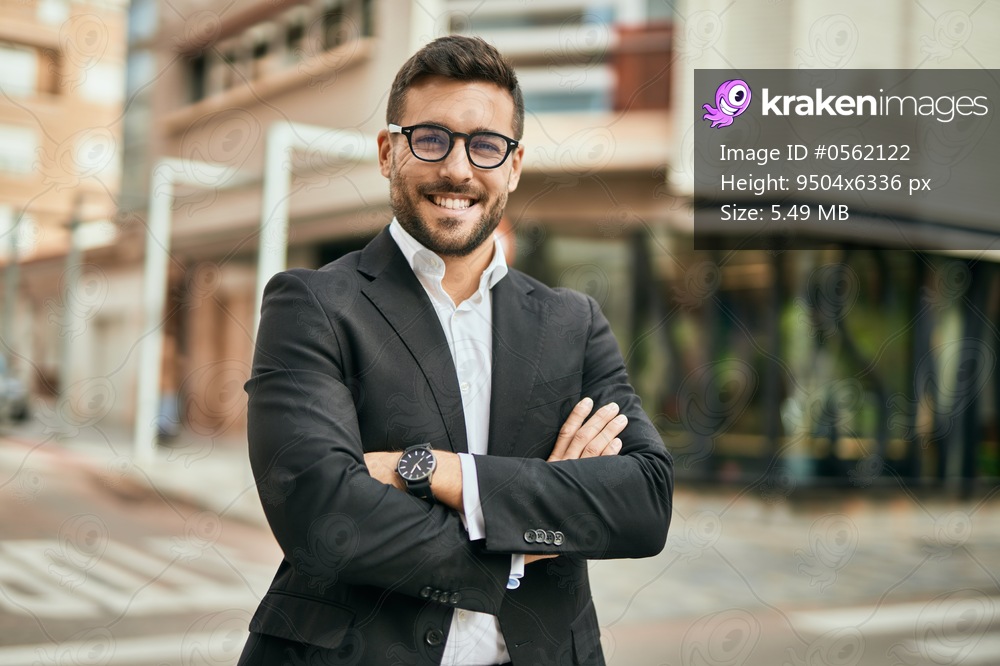 Young hispanic businessman with arms crossed smiling happy at the city.
