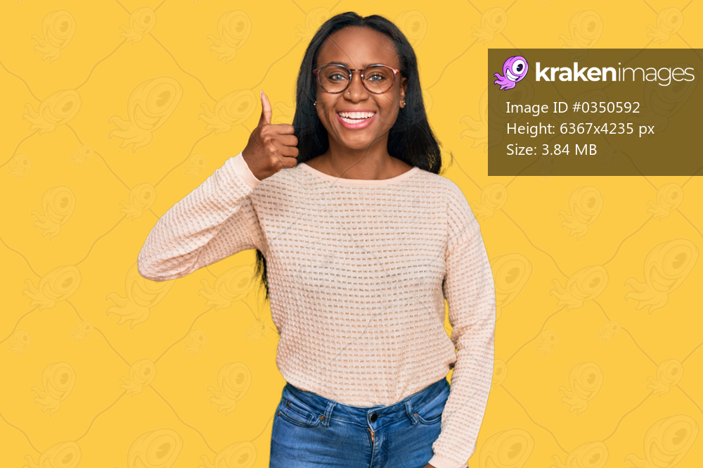 Young black woman wearing casual clothes and glasses smiling happy and positive, thumb up doing excellent and approval sign 