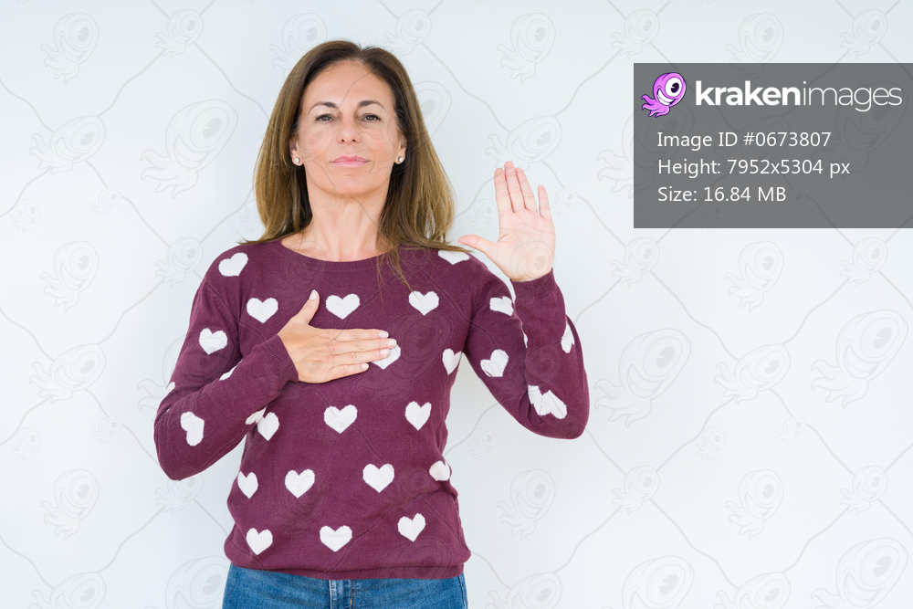 Beautiful middle age woman wearing heart sweater over isolated background Swearing with hand on chest and open palm, making a loyalty promise oath