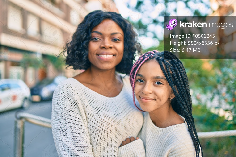 Beautiful african american mother and daughter smiling happy and hugging. Standing with smile on face standing at the city.