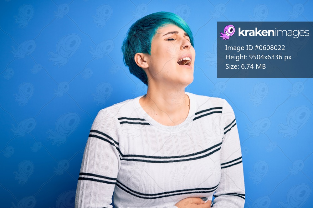 Young beautiful woman with blue fashion hair wearing casual sweater standing at studio with hand on stomach because nausea, painful disease feeling unwell. Ache concept.