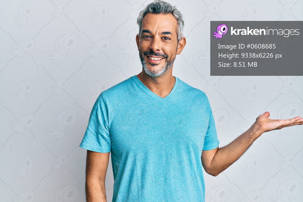 Middle age grey-haired man wearing casual clothes smiling cheerful presenting and pointing with palm of hand looking at the camera. 